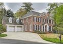 Stately brick home featuring a two-car garage, long driveway, and lush green landscaping around the property at 4503 Payton Oaks Ne Pl, Atlanta, GA 30345