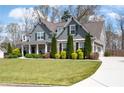 Charming two-story home boasts an inviting front porch and well-manicured front yard with mature landscaping at 1344 Chipmunk Forest Chase, Powder Springs, GA 30127