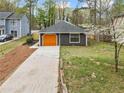 View of the home displaying the driveway leading to an orange garage door, and mature landscaping at 4540 Bryant Rd, Buford, GA 30518