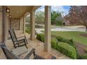 Inviting covered porch with rocking chairs overlooking manicured landscaping and a quiet street at 5224 Brendlynn Dr, Suwanee, GA 30024