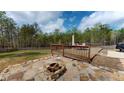 Outdoor area boasts a wooden deck, stone patio, and fire pit, surrounded by lush greenery and a wooden fence at 313 Bonnie Sue Dr, Villa Rica, GA 30180