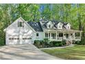 Beautiful home exterior featuring a two-car garage, mature trees, a front lawn, and a front porch at 2100 Kings Valley Dr, Lawrenceville, GA 30043