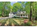 Beautiful home exterior with large front lawn, lush mature trees, and a charming front porch at 2100 Kings Valley Dr, Lawrenceville, GA 30043
