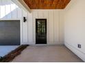 Covered front entrance featuring wood ceiling and a sleek black front door and gray garage door at 2526 Abner Nw Pl, Atlanta, GA 30318