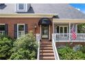 Inviting entryway with brick steps leading to a covered porch and a decorative glass front door at 2610 Ginger Dr, Buford, GA 30519