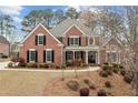 Elegant two-story brick home with manicured landscaping, showcasing a covered front porch and classic architectural details at 214 Cedar Woods Way, Canton, GA 30114