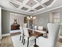 Elegant dining room features coffered ceiling, chandelier, and modern furniture on hardwood floors at 3710 Near Star Ln, Cumming, GA 30028