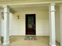 Covered front porch with a brown front door and decorative wall lanterns and supports at 3150 Berkshire Manor Dr, Alpharetta, GA 30022