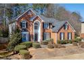 Attractive brick home with manicured landscaping, a covered front entrance, and mature trees surrounding the property at 395 Highland Gate Cir, Suwanee, GA 30024