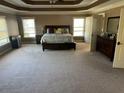 Spacious main bedroom with tray ceilings, carpeted floor, and natural light from large windows at 1210 Del Mar Club Dr, Dacula, GA 30019