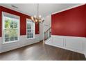 Elegant dining room with rich red walls, classic chandelier, and natural light from large windows at 4461 Kentland Dr, Acworth, GA 30101