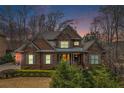 Evening view of a brick home with manicured landscaping, a well-kept lawn, and a covered entryway at 1190 Mosspointe Dr, Roswell, GA 30075