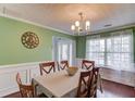 Elegant dining room with wainscoting, hardwood floors, a chandelier, and large windows for ample natural light at 3904 Tristan Way, Suwanee, GA 30024