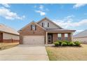 Inviting brick home featuring a well-kept lawn, a two-car garage, and a cozy front porch at 558 Carleton Pl, Locust Grove, GA 30248
