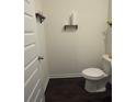 A compact powder room features dark wood floors, a white toilet, and rustic shelves for an efficient design at 184 Grafton St, Hampton, GA 30228