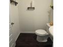 A compact powder room features dark wood floors, a white toilet, and rustic shelves for an efficient design at 184 Grafton St, Hampton, GA 30228