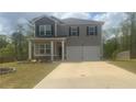 Charming two-story home featuring gray siding, dark shutters, a well-manicured lawn, and a spacious two-car garage at 184 Grafton St, Hampton, GA 30228
