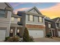 Townhome featuring stone accents on the facade and a two-car garage at sunset at 5890 Vinyard Ln, Cumming, GA 30041