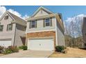 View of townhome showing the two car garage and grassy front yard on a sunny day at 5890 Vinyard Ln, Cumming, GA 30041