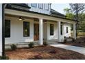 Inviting front porch with stone flooring, white columns, and modern lighting fixtures at 1632 Oleander Sw Dr, Lilburn, GA 30047