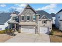 Inviting home featuring a stone facade, a two-car garage, and manicured landscaping at 127 Crest Brooke Dr, Canton, GA 30115