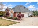 Exterior of a brick home featuring attached garages, manicured landscaping, and a paved driveway at 6730 Waterbury Way, Cumming, GA 30040