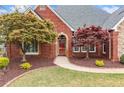 Close-up view of the front entrance with a beautiful brick facade and landscaped garden at 6730 Waterbury Way, Cumming, GA 30040