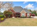 Charming brick home features manicured lawn, mature trees, and a paved walkway leading to the entrance at 6730 Waterbury Way, Cumming, GA 30040