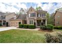 Beautiful two-story home with a brick and siding exterior, green lawn, and mature landscaping at 4421 Wooded Oaks Nw, Kennesaw, GA 30152