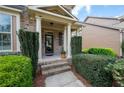 Covered front porch with brick steps and white columns, framed by manicured greenery and decorative shrubs at 4421 Wooded Oaks Nw, Kennesaw, GA 30152