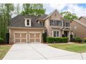 Inviting two-story home featuring a brick facade, well-kept lawn, and a double garage with a long driveway at 4421 Wooded Oaks Nw, Kennesaw, GA 30152