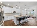 Modern kitchen features white cabinets, stainless steel appliances, an island with barstool seating, and hardwood floors at 6505 Trailway Trce, Cumming, GA 30041