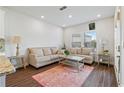Comfortable living room with neutral walls, hardwood floors, two sofas, side tables, and a pink patterned area rug at 6505 Trailway Trce, Cumming, GA 30041