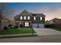 Charming two-story brick home with a well-manicured lawn and a two-car garage at dusk at 368 Sawyer Meadow Way, Grayson, GA 30017