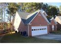 Side view of a brick home showcasing a two-car garage and ample driveway space at 1211 Liverpool Pointe, Lawrenceville, GA 30046