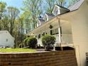 Attractive home with a welcoming porch, retaining wall and lush landscaping on a sunny day at 5851 Swan Walk, Sugar Hill, GA 30518