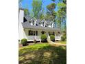 Inviting two-story home featuring a classic white porch, well-manicured lawn, and mature trees at 5851 Swan Walk, Sugar Hill, GA 30518