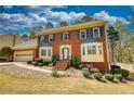 Charming red brick two-story home with blue shutters, bay windows and a well-manicured lawn and landscaping at 4814 Riveredge Cv, Snellville, GA 30039