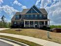 Inviting two-story home with a covered front porch, brick facade, and beautiful blue accent gables at 5458 Summer Pine Pl, Buford, GA 30518