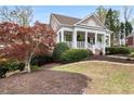 Beautiful front lawn and home with a covered porch, complemented by mature trees at 3902 Butterstream Nw Way, Kennesaw, GA 30144