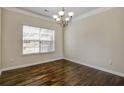 Bright dining room with hardwood floors, a chandelier, and a large window providing natural light at 6793 Oconee Pl, Fairburn, GA 30213