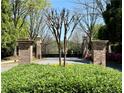 View of the gated entry to this lovely property with brick pillars and mature landscaping at 8070 Georgetown Cir, Suwanee, GA 30024