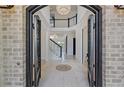 Grand foyer featuring a soaring ceiling, elegant chandelier, white marble flooring, and an arched iron doorway at 5395 Lacosta Ln, Alpharetta, GA 30022