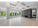 Spacious living room featuring a stone fireplace, coffered ceilings, and large windows providing ample natural light at 5395 Lacosta Ln, Alpharetta, GA 30022
