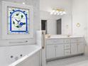 Bright bathroom featuring double vanity, stained glass window, and a soaking tub at 488 Takely Dr, Lawrenceville, GA 30046