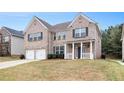 Inviting brick home featuring a two-car garage, lush lawn and cozy front porch for relaxing outdoors at 2036 Broadmoor Way, Fairburn, GA 30213