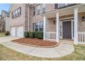 Close-up of a charming front porch with white pillars, well-kept bushes and a tidy yard at 2036 Broadmoor Way, Fairburn, GA 30213