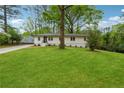 Inviting single-story home with lush green lawn and a tree in the front yard at 1232 Andrews Dr, Marietta, GA 30062