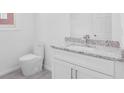 Bathroom with a modern toilet, granite countertop and a white sink and cabinet at 4066 Wild Orchid Ln, Loganville, GA 30052