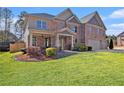 Charming two-story brick home featuring a covered front porch and lush landscaping at 4922 Summer Wind Dr, Buford, GA 30519